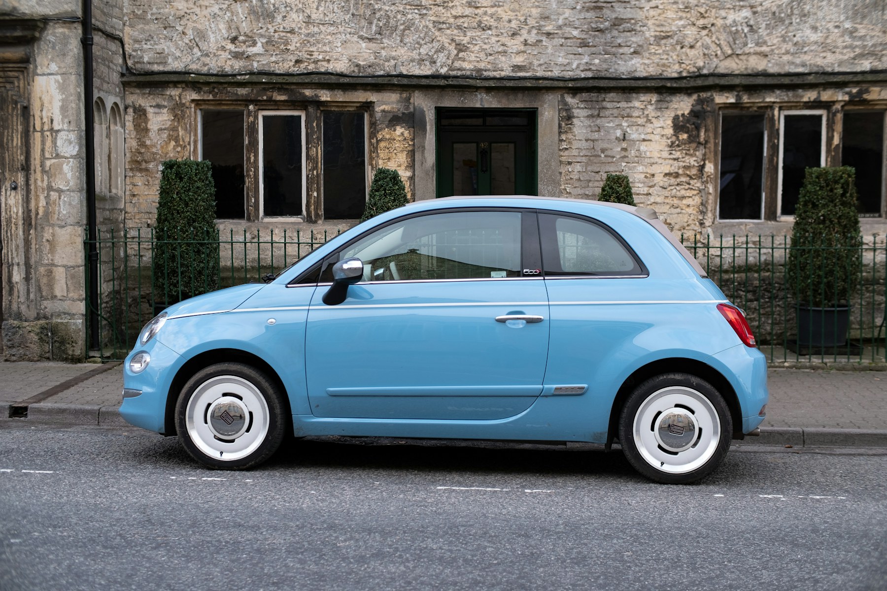 Blue compact city car parked beside a stone building